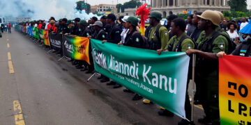 Detailed image of Nigerian police and military in Abuja using tear gas to disperse #FreeNnamdiKanuNow protesters near the Three Arms Zone in October 2025, highlighting the severe security crackdown.